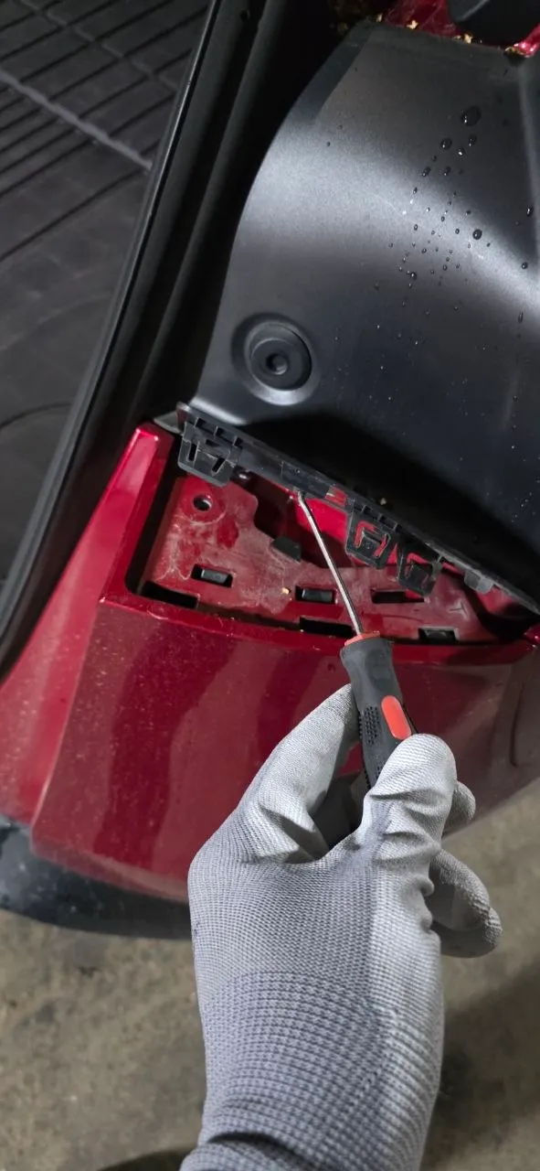 Releasing the bumper corner clips at the tailgate opening with a trim pick