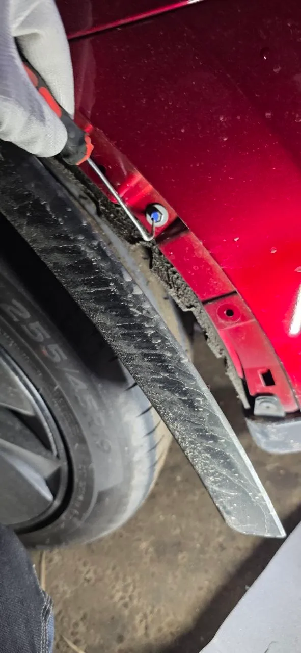 Hidden bumper fastener revealed behind the pulled-back arch liner