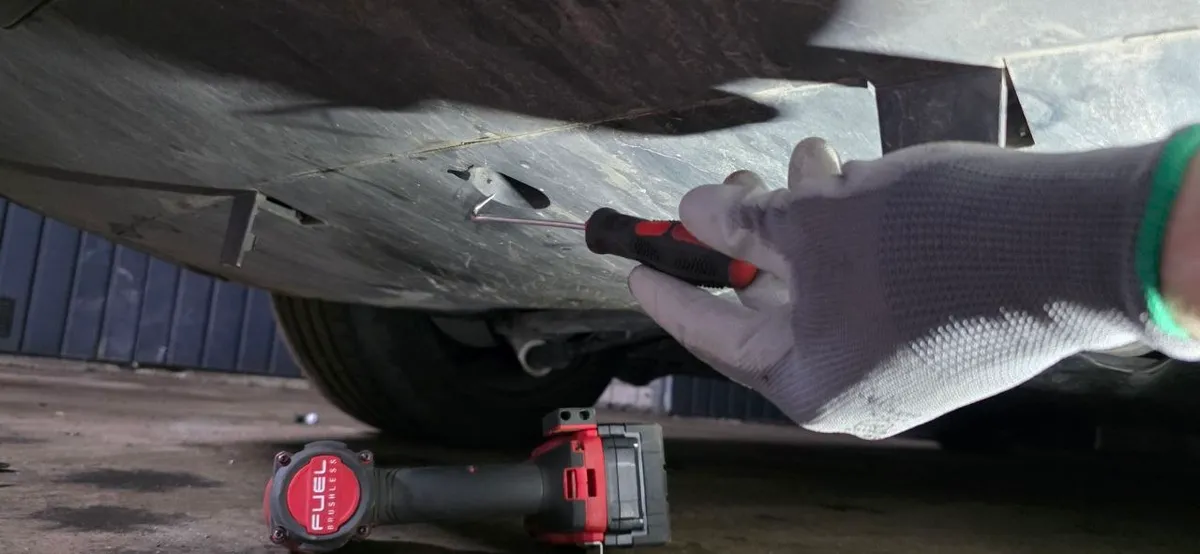Row of underbody clips along the diffuser seam being released with a hook tool