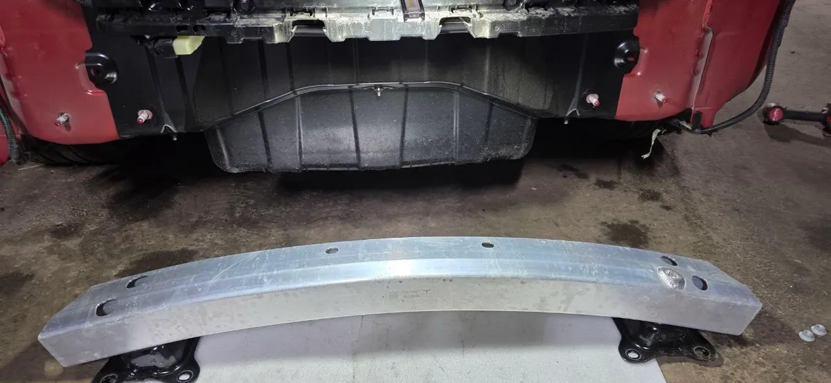 Removed aluminum impact bar lying on foam in front of the car
