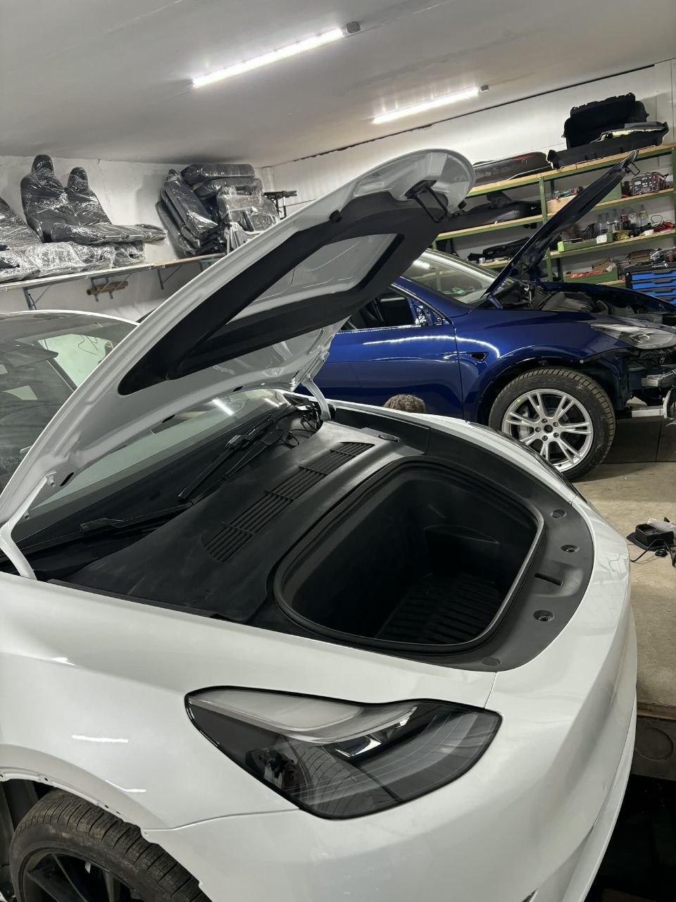 Tesla Model Y with trunk liftgate open in repair workshop
