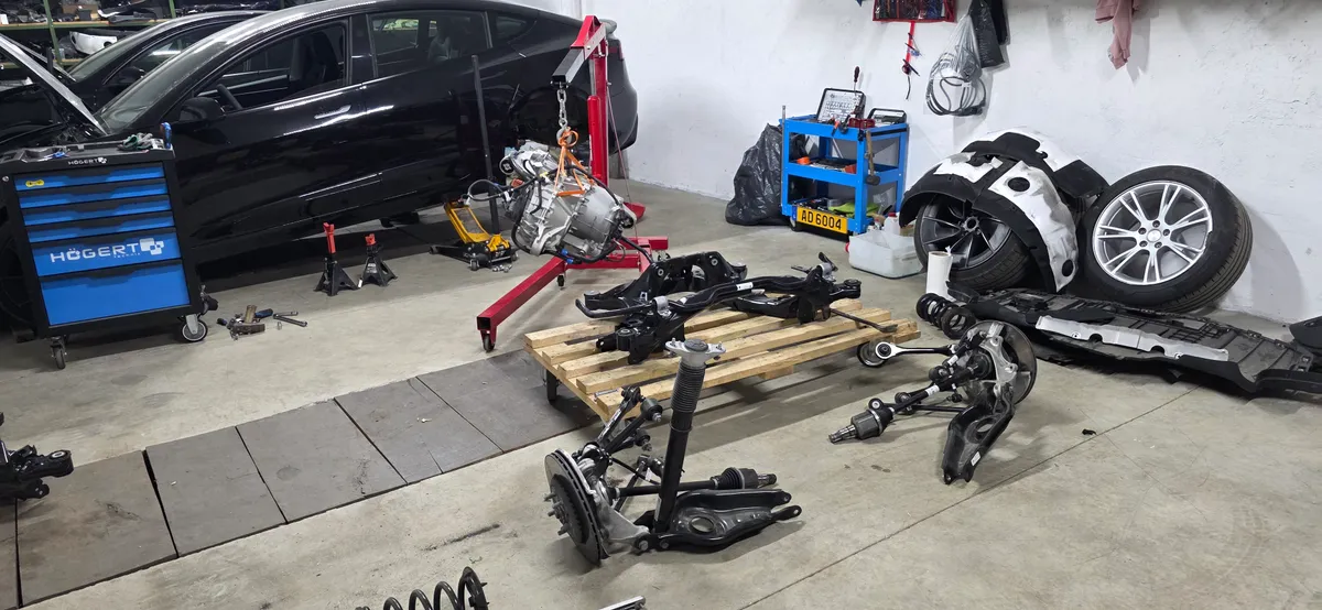 Tesla workshop with drive unit on hoist and suspension components